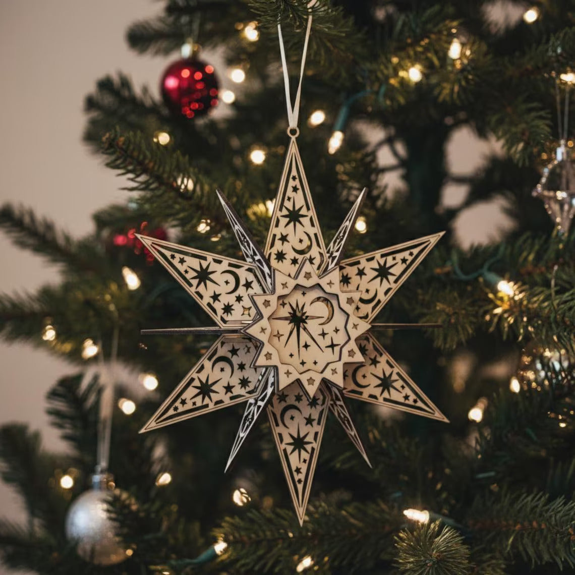 Decorative star ornament on a Christmas tree with lights and other ornaments.