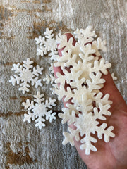 Hand holding white snowflake-shaped cookies on a textured surface