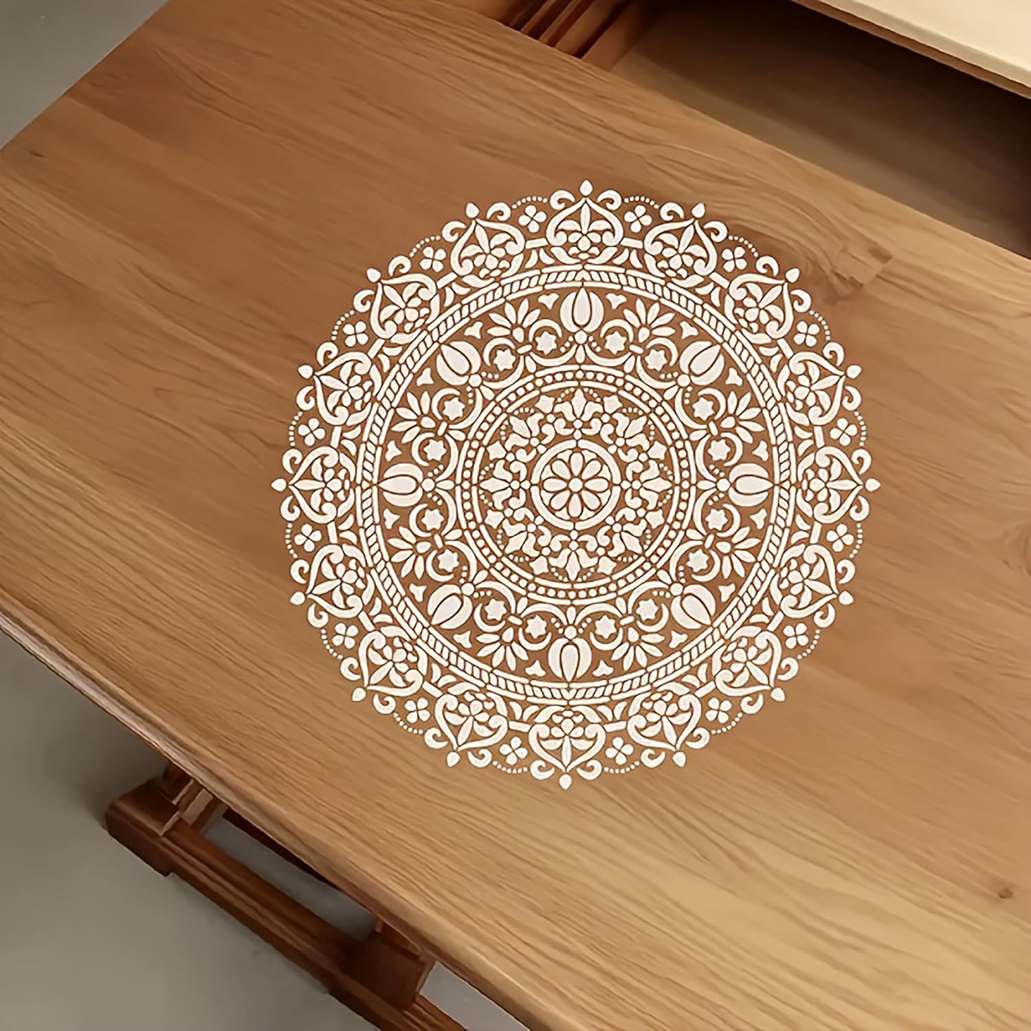 Decorative white mandala design on a wooden surface